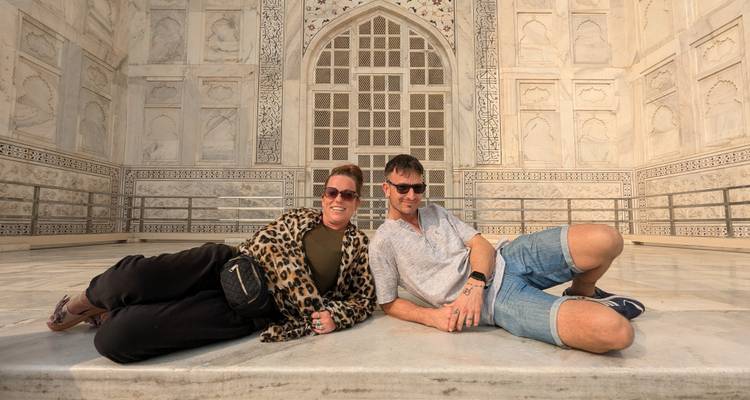 Couple posing while lying in front of the Taj Mahal.