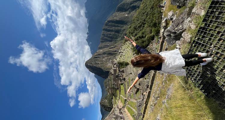 Woman with arms outstretched at Machu Picchu with stunning mountain views.