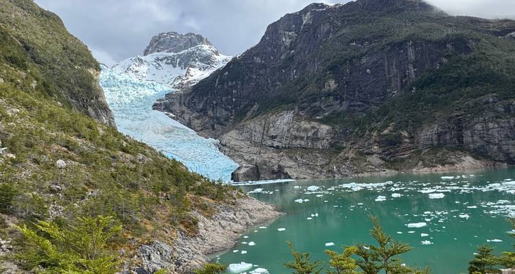 Scenic view of a glacier flowing into a turquoise lake surrounded by mountains.