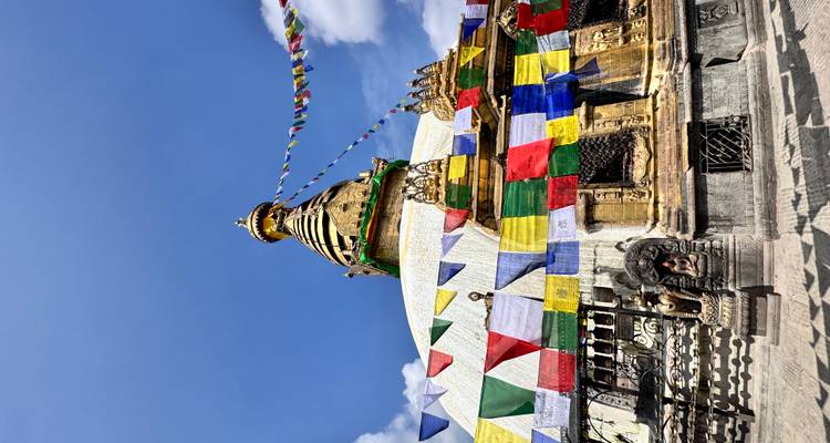 Swayambhunath stupa met gebedsvlaggen tegen blauwe hemel.