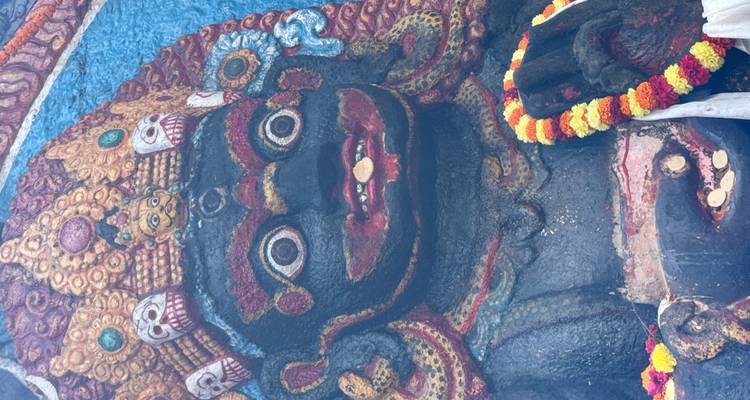 Statue de pierre noire ornée de fleurs colorées.