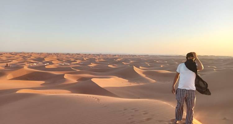 Personne debout sur les dunes de sable dans le désert au coucher du soleil.