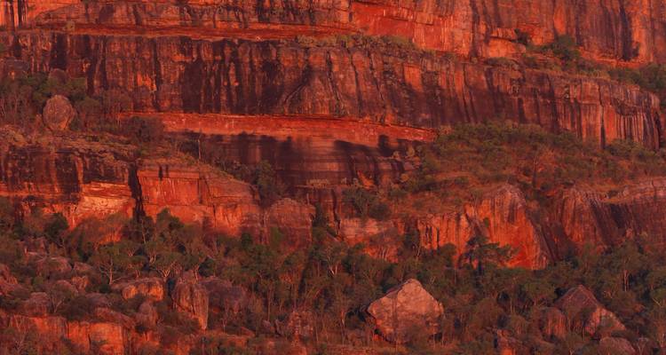 Zerklüftete rote Felsklippen, die von Sonnenlicht beleuchtet werden.