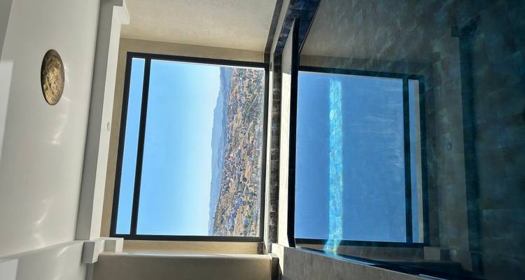 Piscine intérieure avec vue sur une ville marocaine à travers une grande fenêtre.