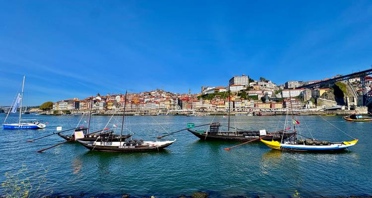 Traditionelle Boote auf einem Fluss mit Blick auf eine Stadtsilhouette.