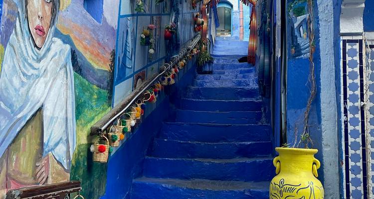 Escalier coloré à Chefchaouen avec œuvres d'art et fleurs.