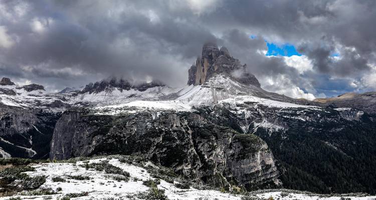 Pics de montagne enneigés sous un ciel nuageux.