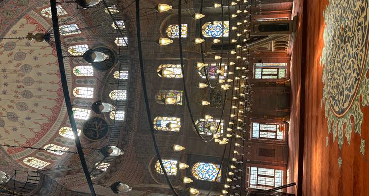 Innenraum einer Moschee mit Buntglasfenstern and Kronleuchtern.