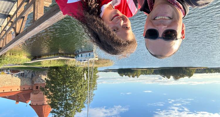 Dos personas con un lago y un castillo de fondo.