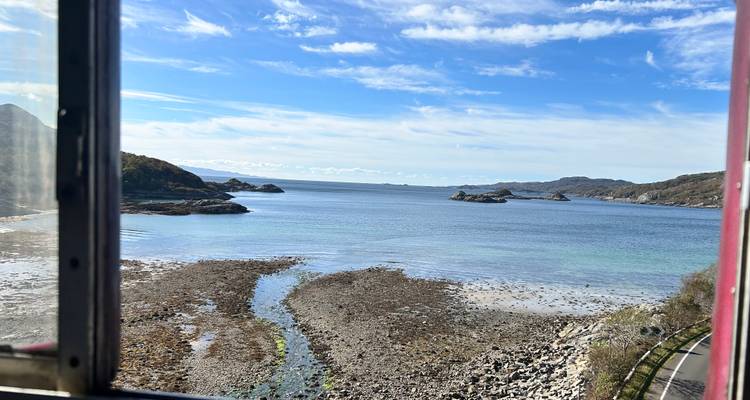 Une vue côtière pittoresque depuis une fenêtre avec des îles au loin.
