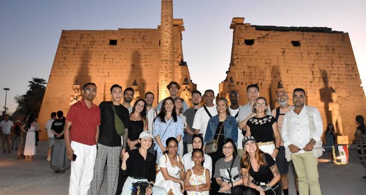 Groupe de personnes posant devant des ruines antiques illuminées