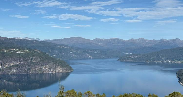 Une vue panoramique d'un fjord entouré de montagnes sous un ciel bleu dégagé.