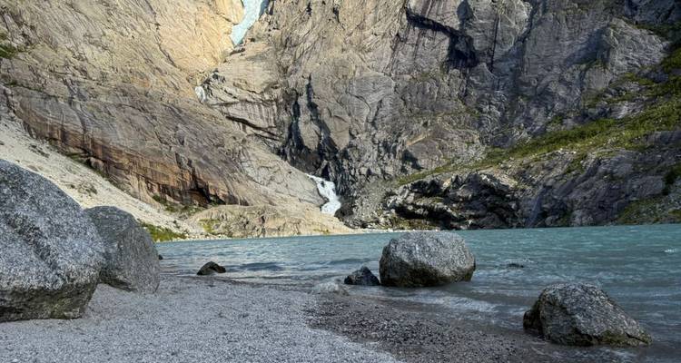 Ein felsiges Seeufer mit Bergen im Hintergrund.