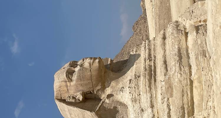 Great Sphinx of Giza with a pyramid in the background under a clear blue sky.