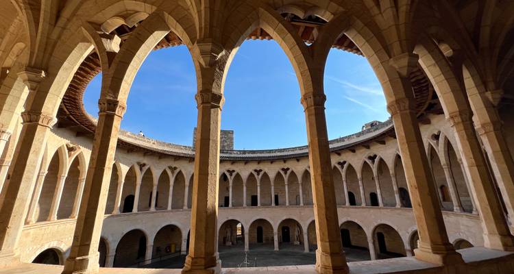 Intérieur d'un bâtiment historique avec des arches donnant sur une cour.