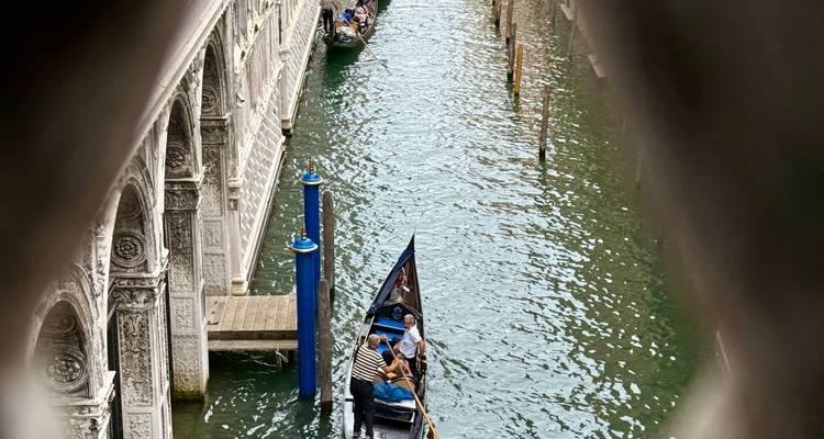 A gondola with people on a Venetian canal.
