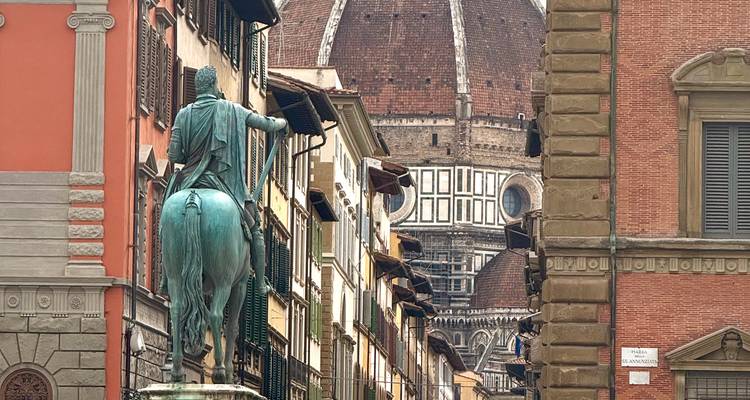 Statue of a horse and rider in front of the Florence Cathedral dome.