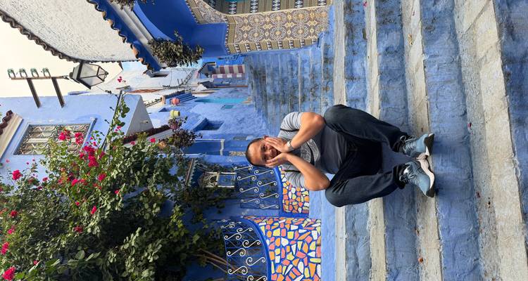 Man sitting on colorful steps in a blue-painted alley.