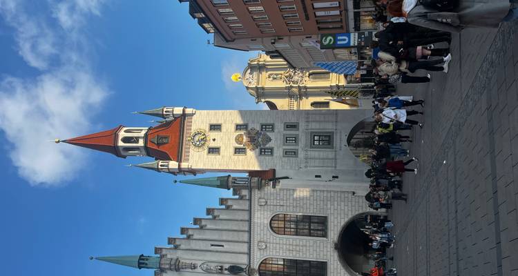 Crowded plaza in front of Munich's New Town Hall with a bright blue sky.