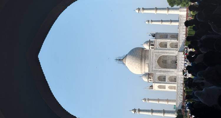 Le Taj Mahal vu à travers une arche, entouré de visiteurs.