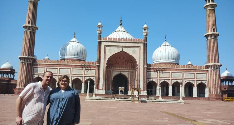 Deux personnes debout devant une grande mosquée avec de larges coupoles.