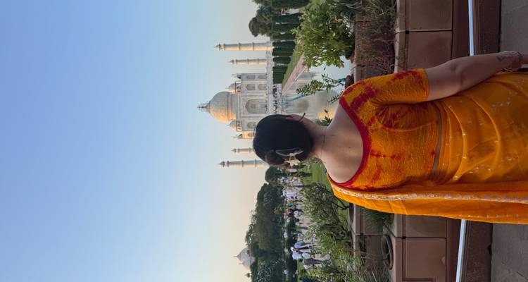 Femme en sari regardant le Taj Mahal au coucher du soleil.