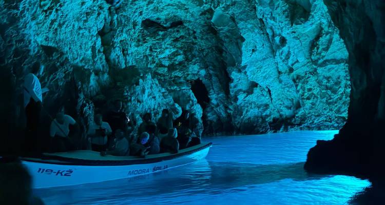 Visite en bateau dans une grotte éclairée en bleu.
