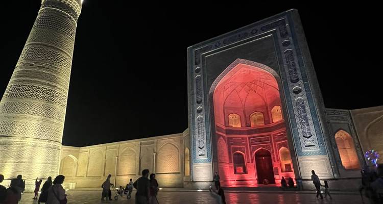 Des gens marchant devant une mosquée magnifiquement éclairée la nuit.