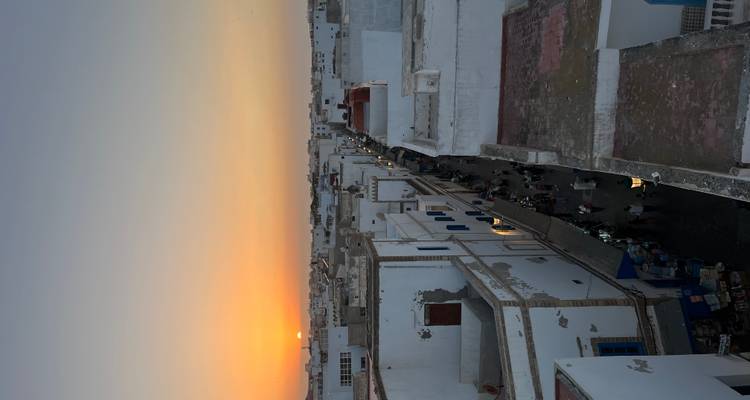 Cityscape at sunset with white buildings and a clear view of the horizon.
