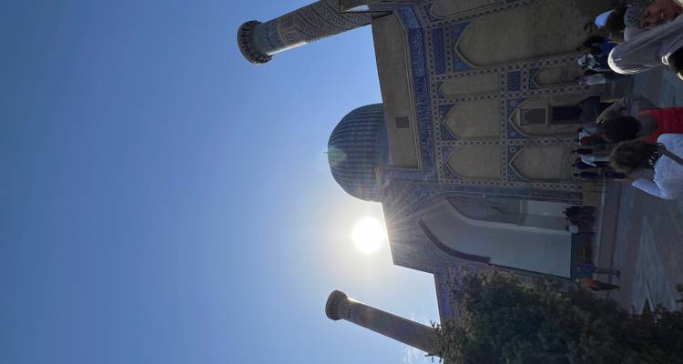 Visiteurs à l'entrée d'une mosquée avec le soleil qui scintille au-dessus.