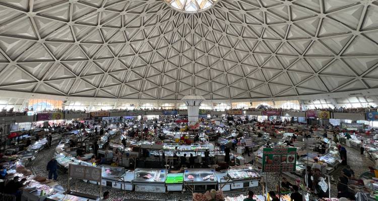 Interior de un mercado bajo un gran techo abovedado.
