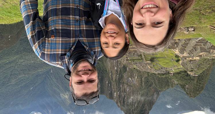 Trois personnes souriantes avec le Machu Picchu en arrière-plan.