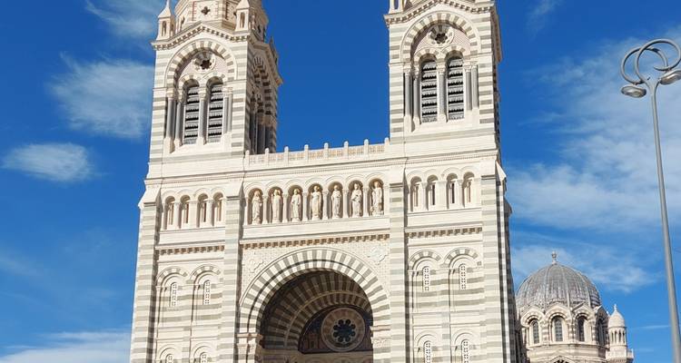 Large cathedral with striped facade and two towers.
