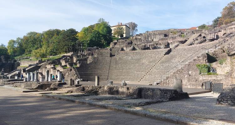 Groot stenen amfitheater met bomen en historische gebouwen.
