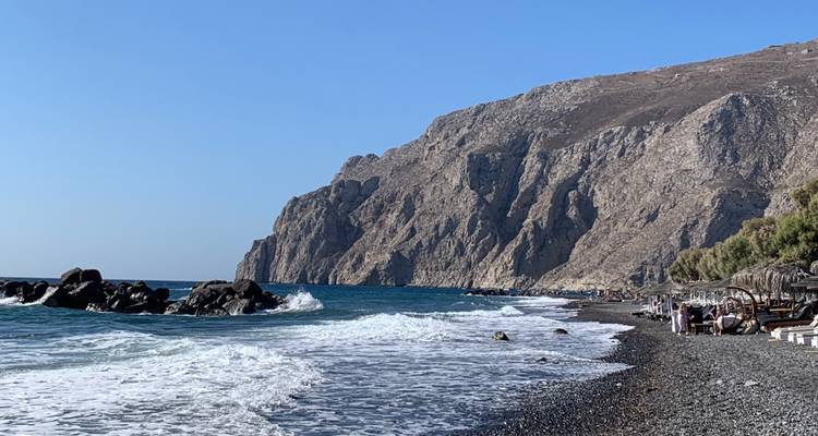 Rocky beach with waves crashing and cliffs in the background.