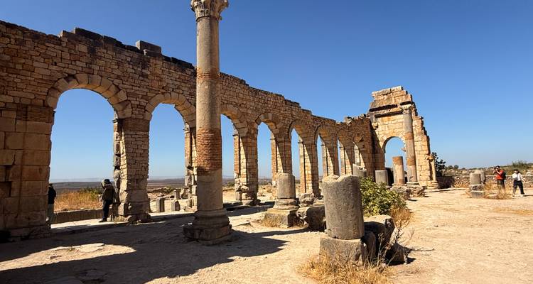 Plaza histórica con columnas de piedra y una torre.