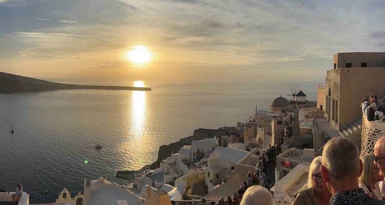 Vue du coucher de soleil sur une ville côtière de Santorin avec des gens et des bâtiments.