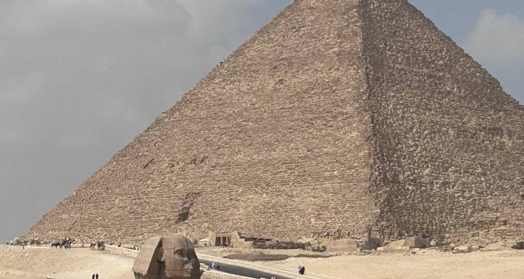 La Grande Pyramide et le Sphinx sous un ciel nuageux.