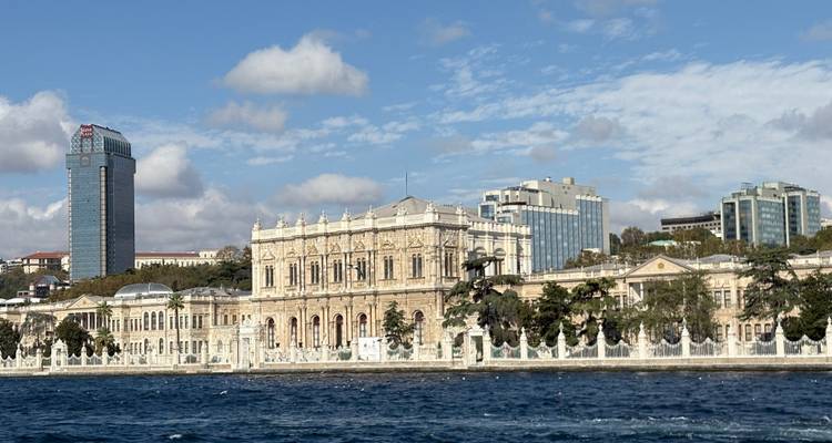Elegant riverside palace seen from the water with a backdrop of modern buildings.