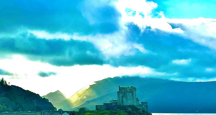 A scenic view of a castle by a loch with dramatic lighting.