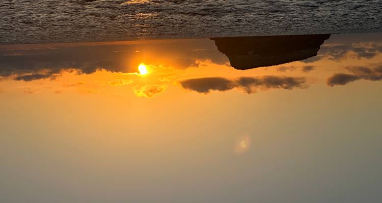 Ocean sunset with silhouetted island and beautiful sky.
