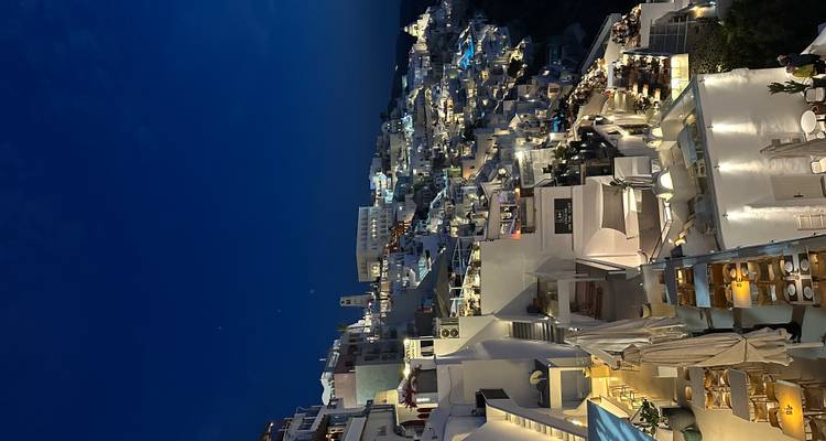Night view of Santorini with illuminated buildings on the cliff.