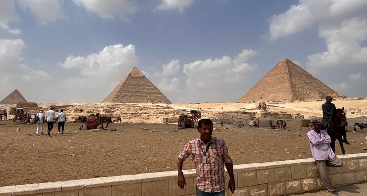Les Pyramides de Gizeh avec des touristes et des chameaux au premier plan.