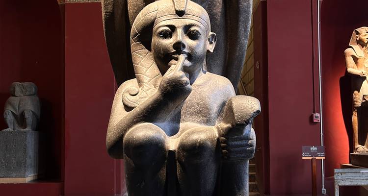 Une statue d'une divinité de l'Égypte antique dans un cadre muséal.