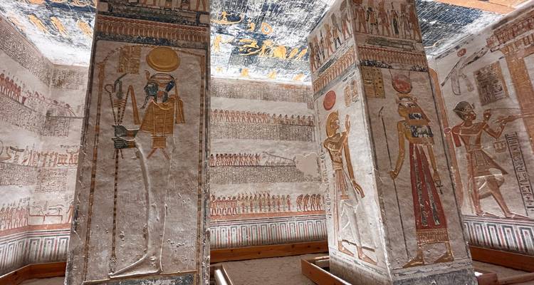 Intérieur d'une tombe avec des hiéroglyphes et des peintures murales colorées.