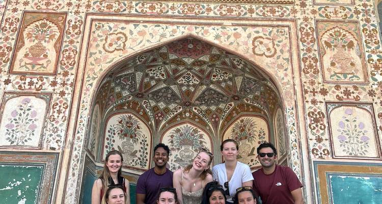 Grupo posando frente a una pared de edificio ornamentada y colorida.