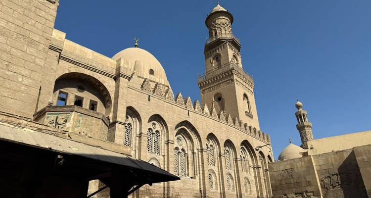 Kuppel und Türme einer alten Moschee vor klarem Himmel.