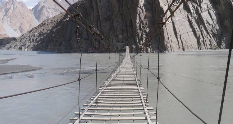 Suspension bridge over a river with rocky cliffs.