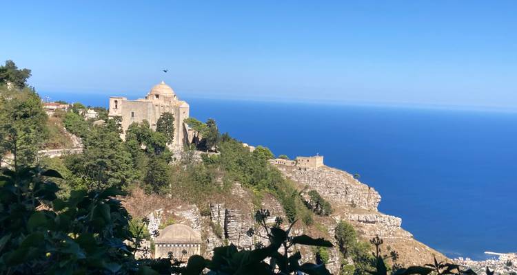 Ville perchée avec des structures historiques surplombant la mer.