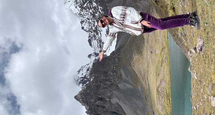 Personne posant avec des montagnes enneigées et un lac.